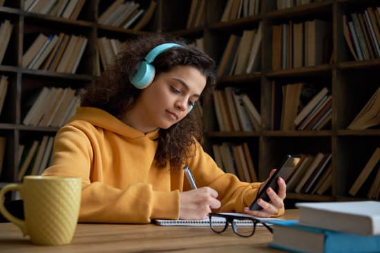 Ein Mädchen lernt mithilfe einer Smartphone-App, während sie Musik über ihre Kopfhörer hört.