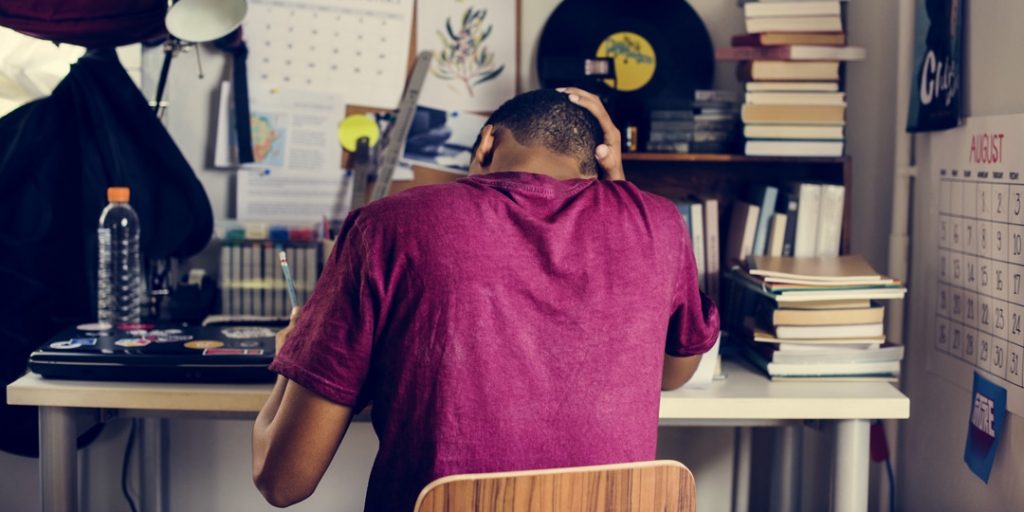 Ein Schüler lernt in seinem Zimmer und leidet unter Leistungsdruck.